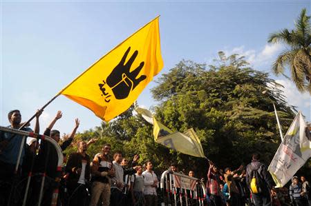 Students of Cairo University, who are supporters of the Muslim Brotherhood and ousted Egyptian President Mohamed Mursi, wave a flag bearing the "Rabaa" sign during a protest against the military and interior ministry in front of at the main gate of the university in Cairo December 9, 2013. REUTERS/Stringer