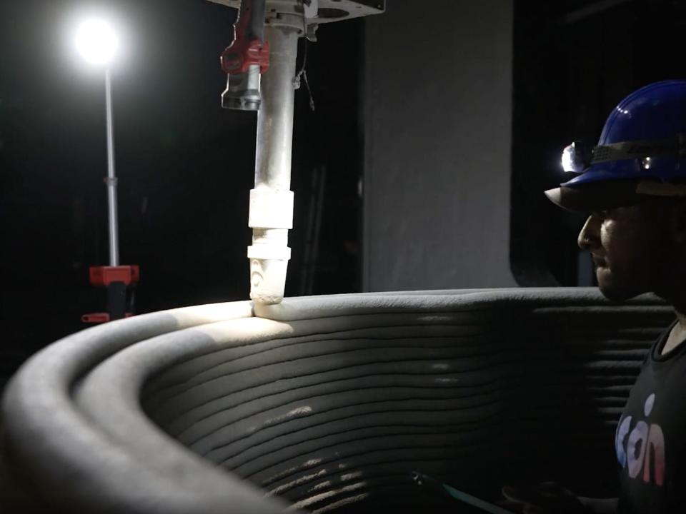 A person monitoring Icon's 3D printer at night as it prints out "lavacrete."