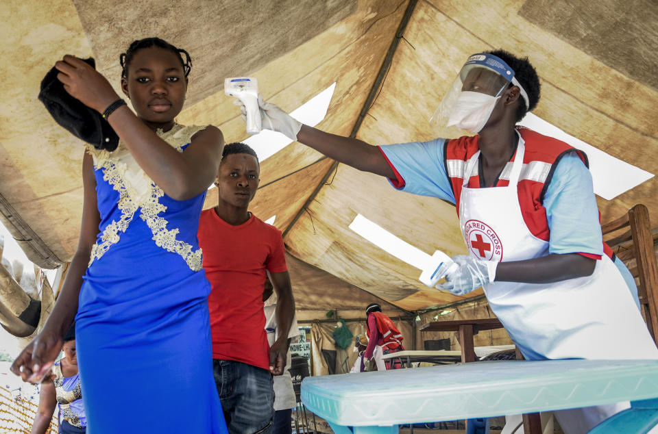 People coming from Congo have their temperature measured to screen for symptoms of Ebola, at the Mpondwe border crossing with Congo, in western Uganda Friday, June 14, 2019. In Uganda, health workers had long prepared in case the Ebola virus got past the screening conducted at border posts with Congo and earlier this week it did, when a family exposed to Ebola while visiting Congo returned home on an unguarded footpath. (AP Photo/Ronald Kabuubi)