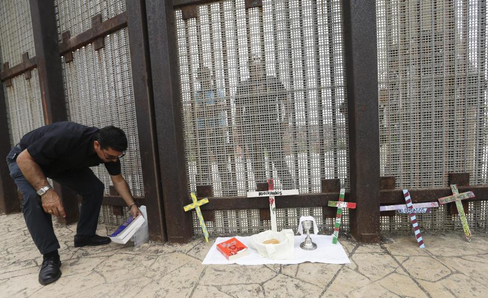 In this July 14, 2013 photo, Father Agustin Mendez prepares to celebrate a Sunday Mass along the fence between San Diego and Tijuana, Mexico. San Diego is a border city but it often does not feel like one despite the fact its center is less than a 20-minute drive to Mexico. The best way to see the border without crossing it is at Border Field State Park, which is at the farthest southwest corner of the United States. (AP Photo/Gregory Bull)