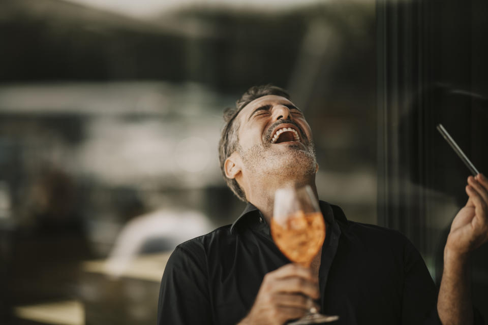 Man laughing holding a glass of drink, in a convivial moment likely related to a tasting event