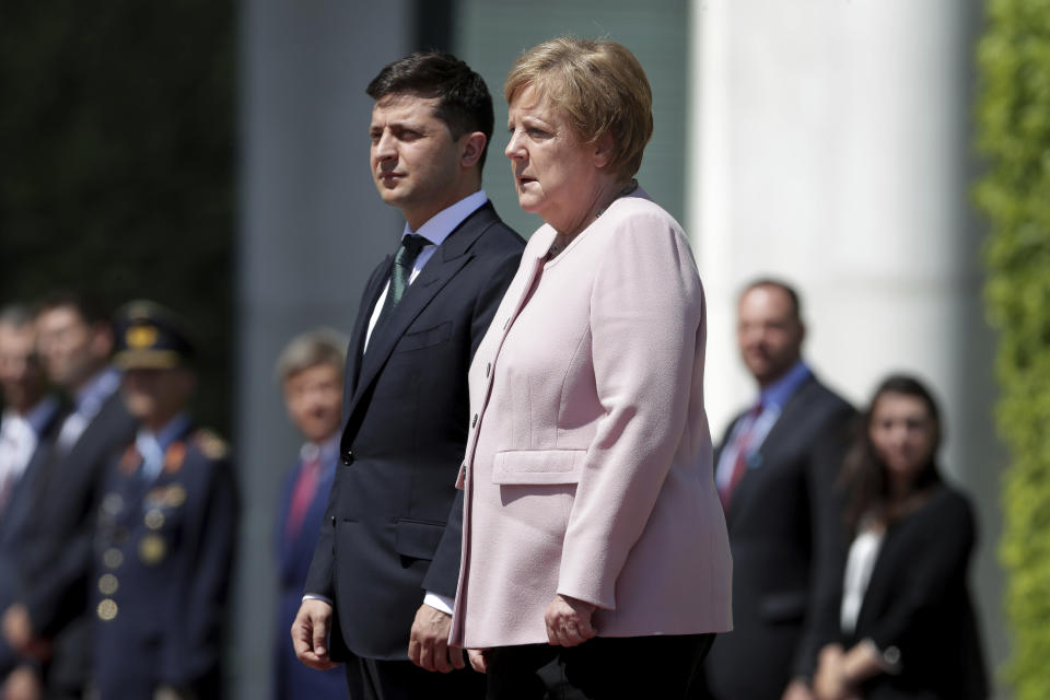 German Chancellor Angela Merkel, right, trembles strong as she and Ukraine's President Volodymyr Zelenskiy, left, attend the national anthems as part of a military welcome ceremony in Berlin, Germany, Tuesday, June 18, 2019. Merkel appeared unwell as she met with Zelenskiy in Berlin, visibly shaking as she received the new Ukrainian president at the chancellery. The incident came Tuesday afternoon as the two stood outside Merkel's office in the hot weather while a military band played their national anthems. Merkel's office had no immediate comment and the two were to hold a press conference later in the afternoon. Following the anthems Merkel seemed better, walking along the red carpet with Zelenskiy into the building, pausing to greet the military band and take a salute. Merkel turns 65 next month. (AP Photo/Michael Sohn)