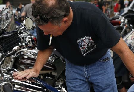 A member of Bikers For Trump checks his motorcycle after arriving for a rally supporting Republican presidential candidate Donald Trump near the Republican National Convention in Cleveland, Ohio, U.S. July 18, 2016. REUTERS/Lucas Jackson