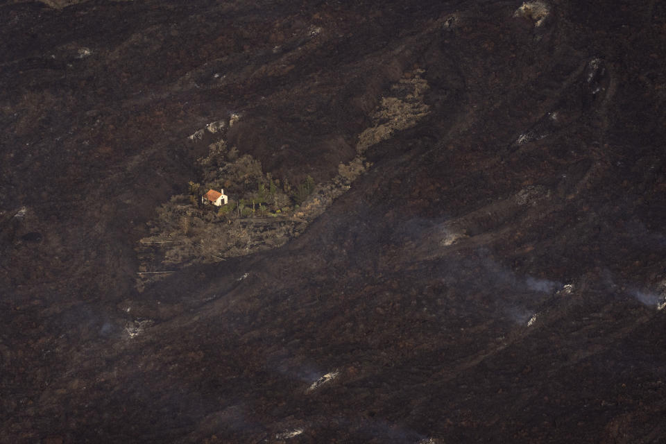 Lava from a volcano eruption surrounds a house on the island of La Palma in the Canaries, Spain, Thursday, Sept. 23, 2021. A volcano on a small Spanish island in the Atlantic Ocean erupted on Sunday, forcing the evacuation of thousands of people. Experts say the volcanic eruption and its aftermath on a Spanish island could last for up to 84 days. (AP Photo/Emilio Morenatti, Pool)