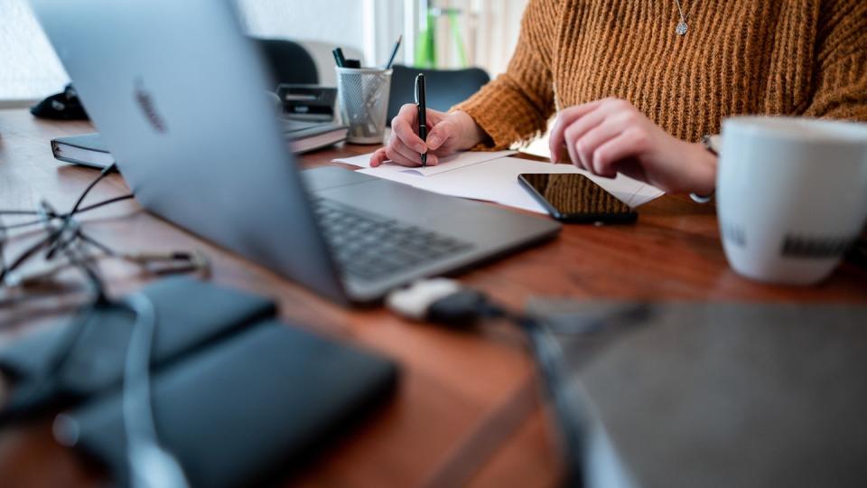 Eine Frau sitzt mit einem Laptop an einem Tisch im Homeoffice.