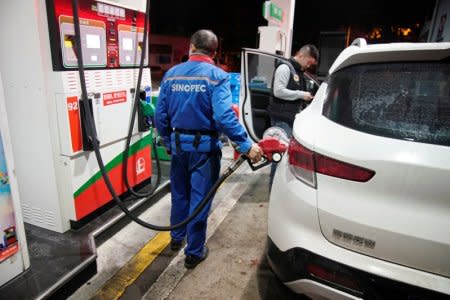 FILE PHOTO: A gas station attendant pumps fuel into a customer's car at a gas station in Shanghai, China November 17, 2017. REUTERS/Aly Song/File Photo