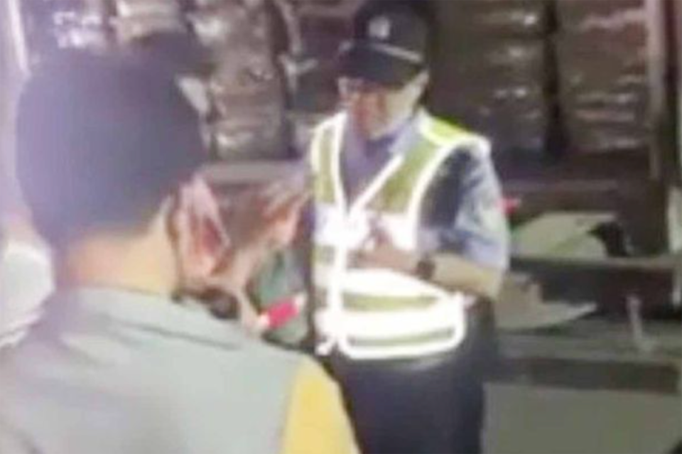 People speak with man in hi vis vest next to courier truck in China.