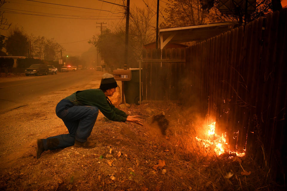 Carolyn Potter tries to save her house from the flames as she throws dirt on her fence in Ventura County's Casita Springs community.