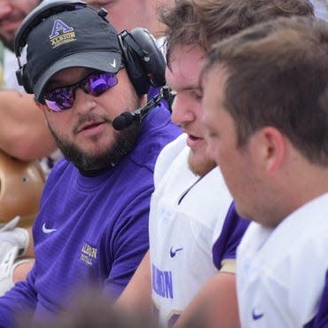 Albion College football coach Dustin Beurer (Britton Deerfield) sits with his team during a game this season.