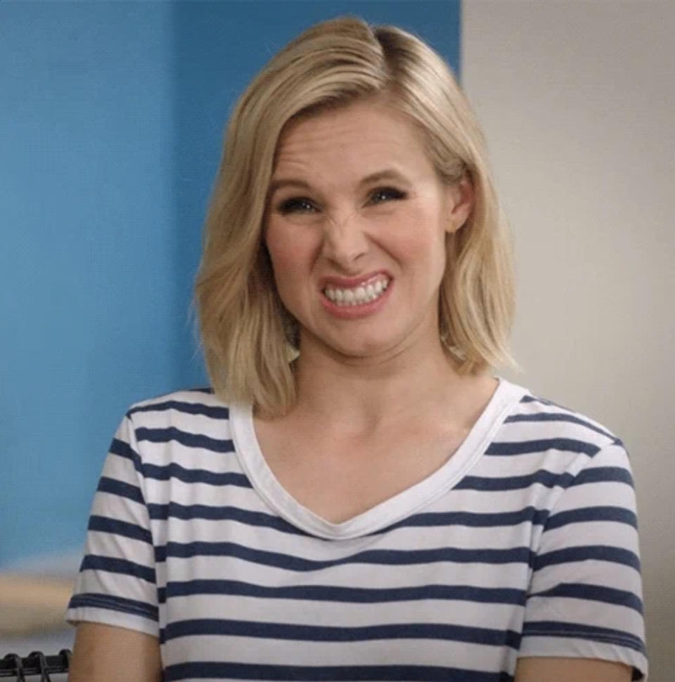 Kristen Bell smiles with a playful expression, wearing a short-sleeved, striped shirt