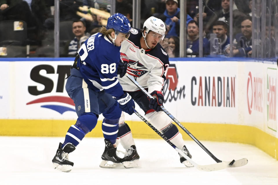 Toronto Maple Leafs right winger William Nylander (88) fights for the puck against Columbus Blue Jackets center Cole Sillinger (34) during the first period of an NHL hockey game Saturday, Feb. 11, 2023, in Toronto. (Jon Blacker/The Canadian Press via AP)