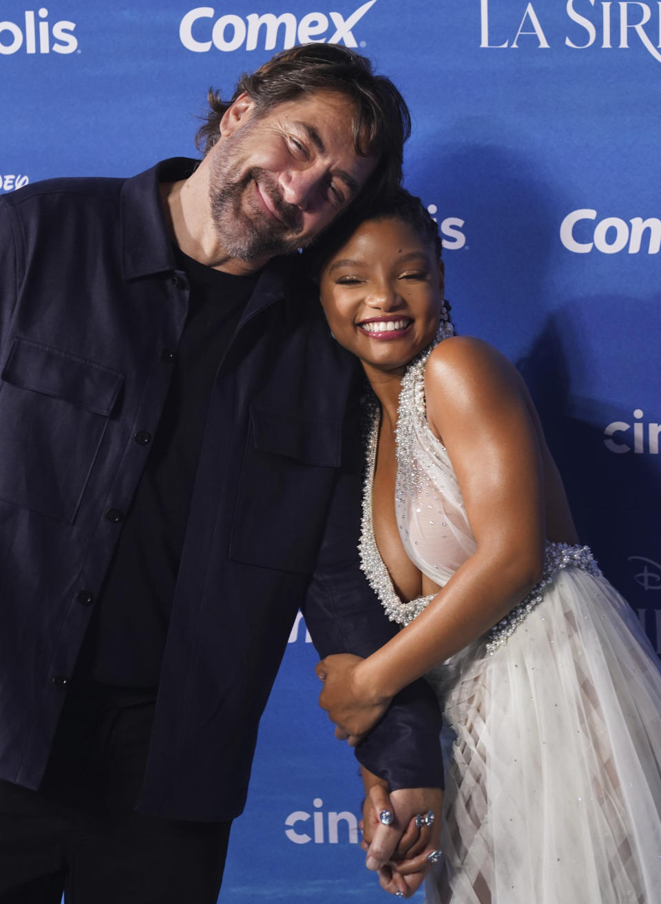 Los actores Halle Bailey, derecha, y Javier Bardem posan en la alfombra azul de la película La Sirenita en la Ciudad de México el 11 de mayo de 2023. (Foto AP/Marco Ugarte)