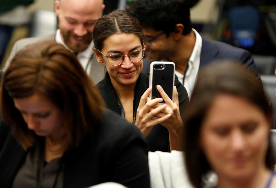 Alexandria Ocasio-Cortez looks at her phone. (Photo: Joshua Roberts/Reuters)