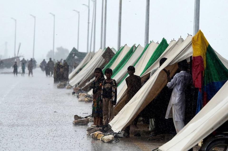 People who fled their flood-hit homes stand outside temporary tents set along a road during a heavy monsoon rainfall in Pakistan's Sukkur of Sindh province, on Aug. 27, 2022.<span class="copyright">Asif Hassan—AFP via Getty Images</span>