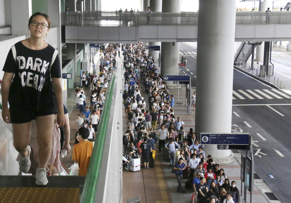 Stranded passengers queue up in lines to wait for special buses at Kansai International Airport following a powerful typhoon in Osaka, western Japan, Wednesday, Sept. 5, 2018. About 3,000 passengers stranded by Typhoon Jebi overnight at the offshore Japanese airport begun returning by boat and by bus Wednesday morning over a partially damaged bridge to the mainland. (Kyodo News via AP)