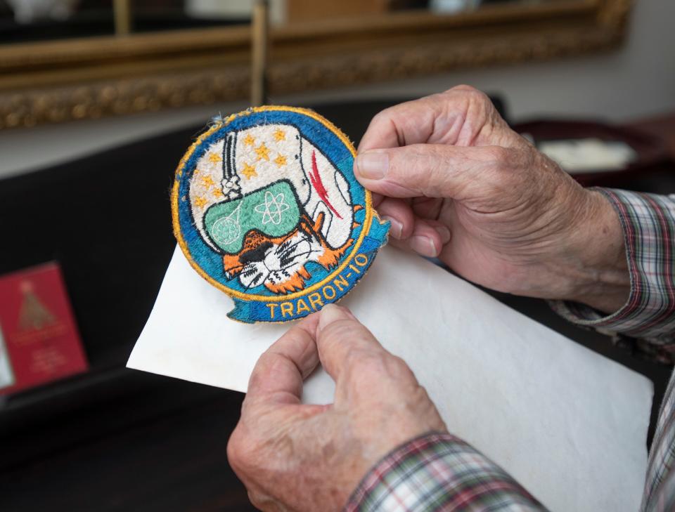 Morris Drees holds a squadron patch from when he was a naval aviator as he talks about his experiences at his home in Gulf Breeze on Wednesday.