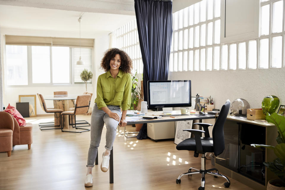 A woman smiling and a work outfit with sneakers