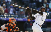 Colorado Rockies' Raimel Tapia, right, follows the flight of his single to drive in two runs with San Francisco Giants catcher Buster Posey in the fourth inning of a baseball game Wednesday, May 5, 2021, in Denver. (AP Photo/David Zalubowski)