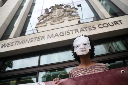 A demonstrator wearing a mask depicting Julian Assange protests outside of Westminster Magistrates Court, where a case hearing for U.S. extradition of Wikileaks founder Julian Assange is held, in London