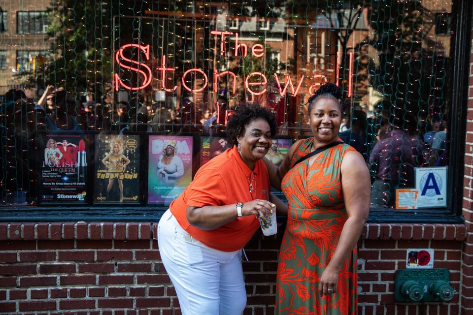 Two women standing in front of the The Stonewall window.