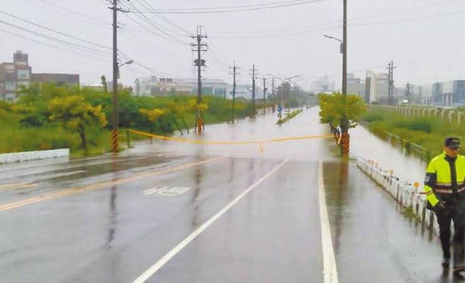 暴雨25日晚間至26日襲擊高雄，造成永安區永安路淹水，警方到場警戒。（林瑞益攝）