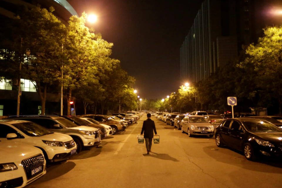 Han Liqun, an HR manager at RenRen Credit Management Co. in Beijing, carries beer and food for his colleagues as he walks to the office after midnight on April 27, 2016. (Jason Lee/Reuters)