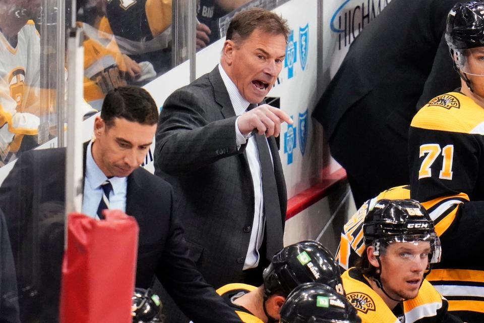 Boston Bruins head coach Bruce Cassidy, center, gives instructions during the third period of an NHL hockey game against the Pittsburgh Penguins.