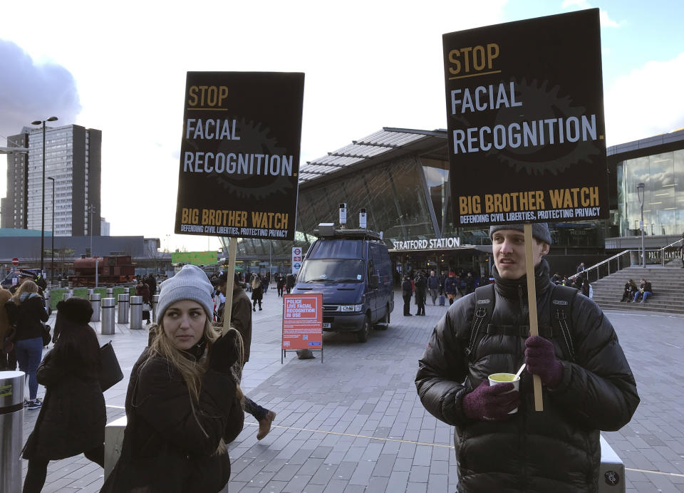 Rights campaigner Silkie Carlo, left, demonstrates in front of a mobile police facial recognition facility outside a shopping centre in London Tuesday Feb. 11, 2020, “We don't accept this. This isn't what you do in a democracy," said Carlo, director of privacy campaign group Big Brother Watch. London police started using facial recognition surveillance cameras mounted on a blue police van on Tuesday to automatically scan for wanted people, as authorities adopt the controversial technology that has raised concerns about increased surveillance and erosion of privacy. (AP Photo/Kelvin Chan)