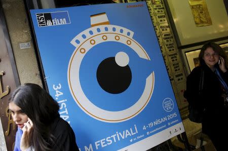 People speak on their mobile phones next to a banner of Istanbul Film Festival at the entrance of Atlas movie theatre in Istanbul April 14, 2015. REUTERS/Murad Sezer