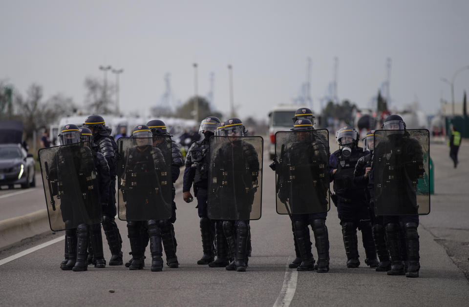 French police officers face oil workers as they block the access to an oil depot in Fos-sur-Mer, southern France, Tuesday, March 21, 2023. The bill pushed through by President Emmanuel Macron without lawmakers' approval still faces a review by the Constitutional Council before it can be signed into law. Meanwhile, oil shipments in the country were disrupted amid strikes at several refineries in western and southern France. (AP Photo/Daniel Cole)