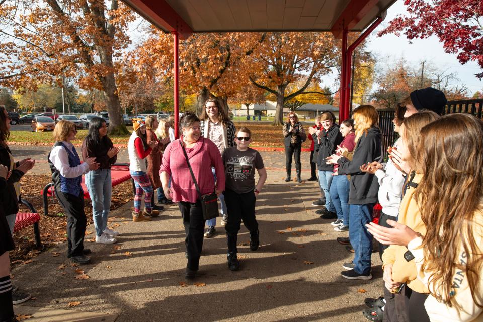 Sam Lockard, center, walks through a welcoming committee of Sparrow Club members at Thurston High School where he was introduced as the first “sparrow” for the new club.