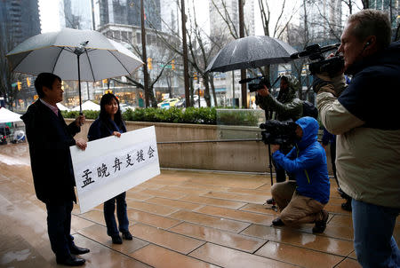 Terence Xu, left and Ada Yu hold a sign supporting Huawei CFO Meng Wanzhou, who was held on an extradition warrant, outside her B.C. Supreme Court bail hearing in Vancouver, British Columbia, Canada December 11, 2018. REUTERS/Lindsey Wasson