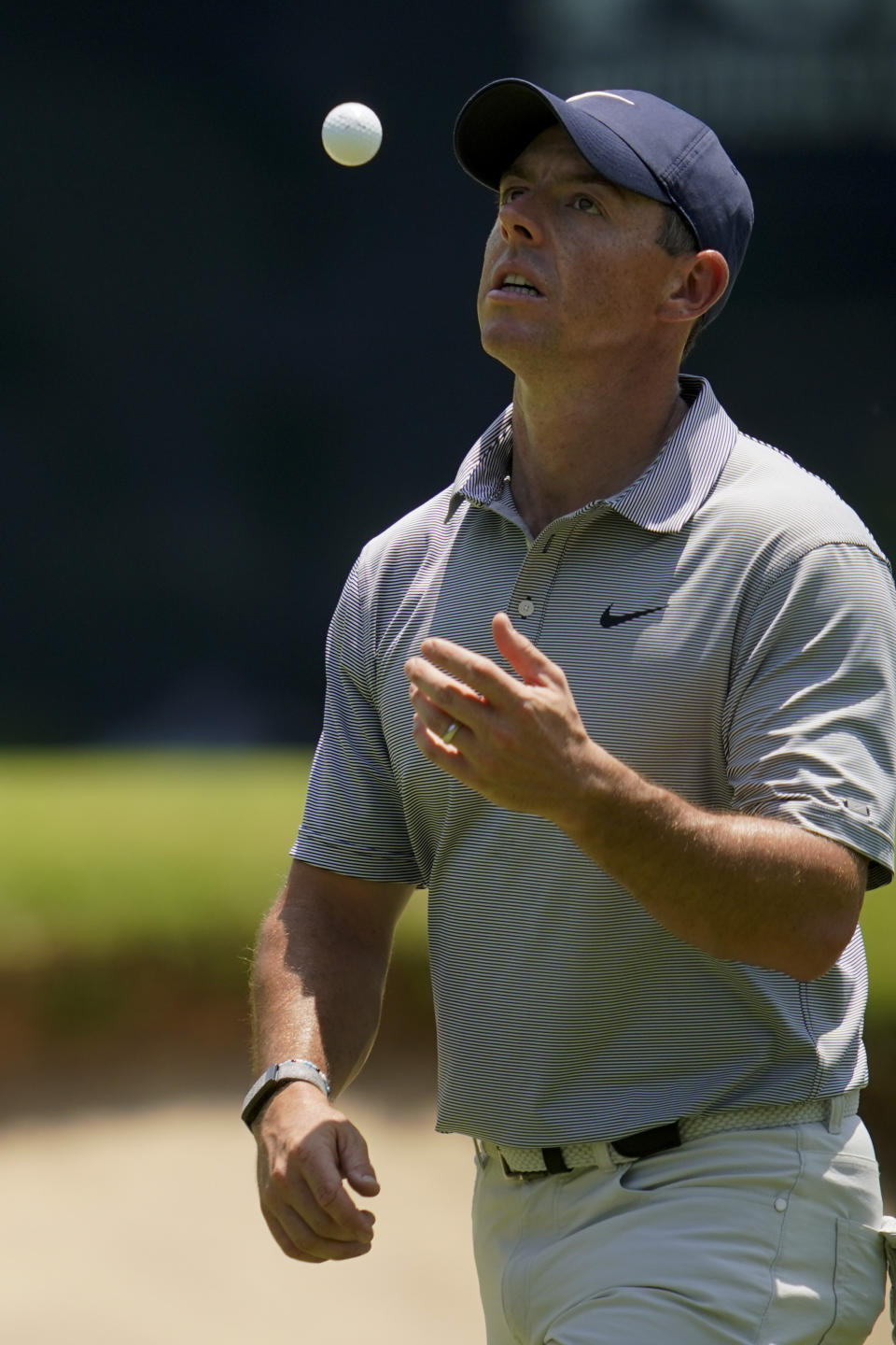 Rory McIlroy, of North Ireland, tosses his ball on the way to the eighth hole during a practice round for the PGA Championship golf tournament, Wednesday, May 18, 2022, in Tulsa, Okla. (AP Photo/Sue Ogrocki)