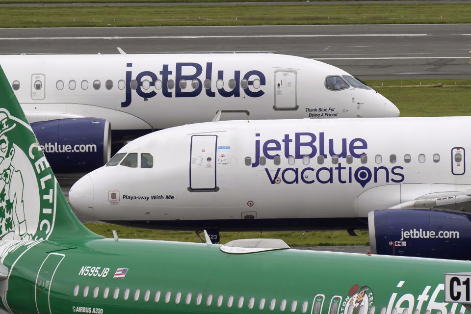 Passenger jets, top and center, taxi on the tarmac past another jet, below, at Boston Logan International Airport, Wednesday, June 28, 2023, in Boston. Travelers are getting hit with delays at U.S. airports again early Wednesday, an ominous sign heading into the long July 4 holiday weekend. (AP Photo/Steven Senne)