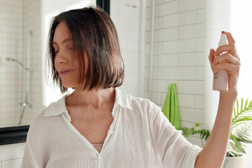 Mature woman spraying hair perfume on hair