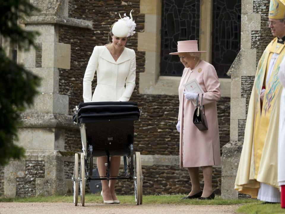 Britain's Queen Elizabeth II stands with Kate the Duchess of Cambridge whilst pushing Princess Charlotte in a pram as they leave after attending the Christening of Britain's Princess Charlotte at St. Mary Magdalene Church in Sandringham, 2015 (AP Photo/Matt Dunham, Pool)