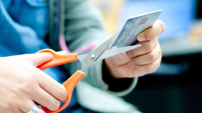 A person using scissors to cut up a credit card