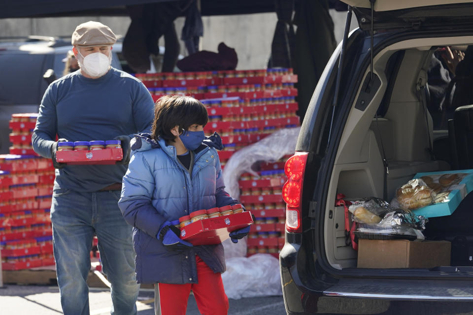 Volunteers hand out food and water at a San Antonio Food Bank drive-through food distribution site held at Rackspace Technology, Friday, Feb. 19, 2021, in San Antonio. (AP Photo/Eric Gay)