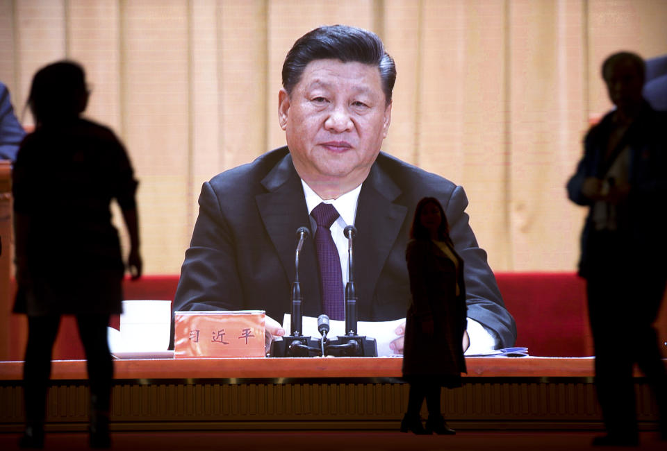 People walk past a video screen displaying an image of Chinese President Xi Jinping at an exhibition commemorating the 40th anniversary of China's Reform and Opening Up Movement at the National Museum in Beijing, Friday, March 1, 2019. Thousands of delegates from around China are gathering in Beijing for next week's annual session of the country's rubber-stamp legislature and its advisory body. (AP Photo/Mark Schiefelbein)