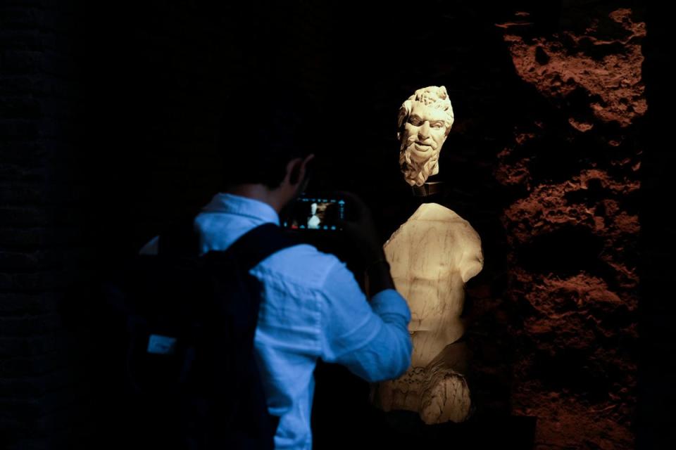 A visitor takes a picture to a statue of Pan during the press preview of the newly-restored Domus Tiberiana. (AP)