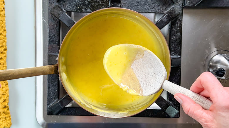 Lemon curd cooking in saucepan with wooden spoon