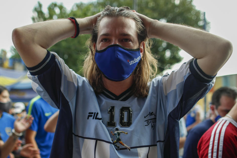 A fan mourns the death of Diego Maradona at the entrance of the Boca Juniors stadium, known as La Bombomera, in Buenos Aires, Argentina, Wednesday, Nov. 25, 2020. The Argentine soccer great who was among the best players ever and who led his country to the 1986 World Cup title before later struggling with cocaine use and obesity, died from a heart attack on Wednesday at his home in Buenos Aires. He was 60. (AP Photo/Natacha Pisarenko)