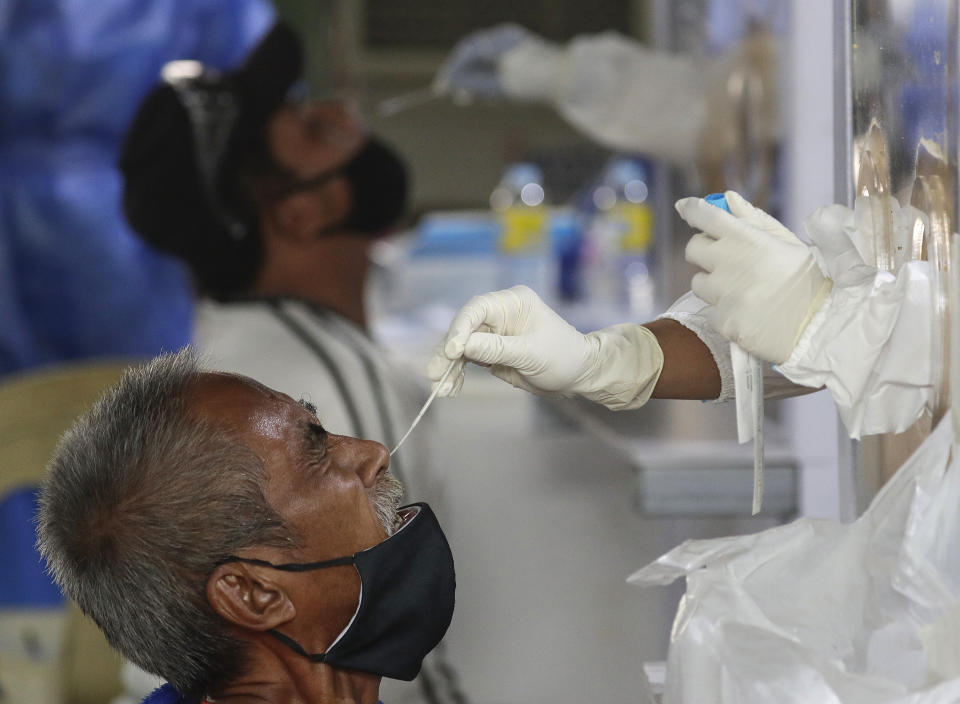 Residents react as they undergo a free COVID-19 swab test in a low income area of Manila, Philippines, Tuesday, Oct. 6, 2020. The city government is providing free swab tests to tricycle and passenger Jeepney drivers in the area in hopes of curbing the spread of the coronavirus. (AP Photo/Aaron Favila)