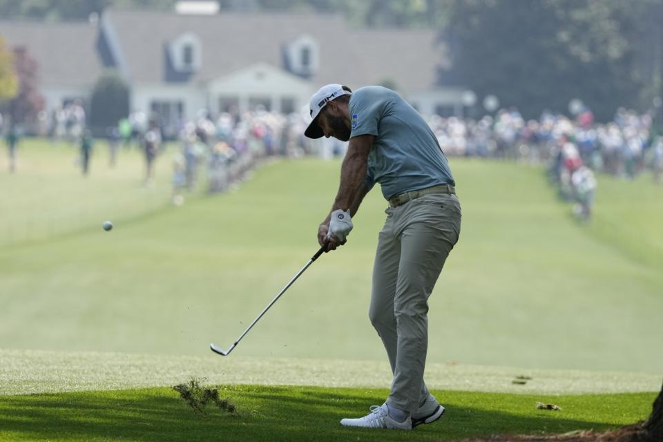 Dustin Johnson digs out a divot hitting from the first fairway