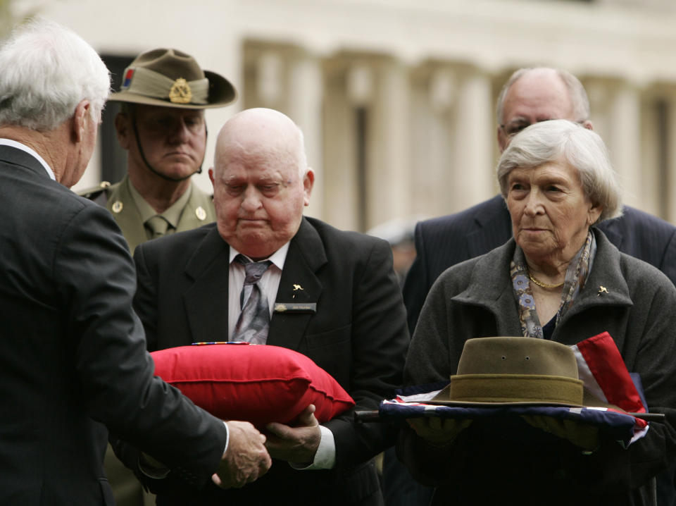 FILE - In this Thursday, Oct. 4, 2007 file photo, Mollie Millis, right, from Brisbane and niece of Australian World War I soldier Private John "Jack" Hunter, holds the presentation of effects from her uncle during a re-burial ceremony at Buttes Military Cemetery in Zonnebeke, Belgium. On another Anzac Day turned lonesome by the global pandemic, solitary actions show all the more how the sacrifices of Australia and New Zealand during World War I are far from forgotten. While global attention will turn at dawn on Sunday to the beaches of Turkey’s Gallipoli where the two emerging countries crafted a sense of nationhood from the horrors of war in April 1915, all along the front line in Europe, small ceremonies will show gratitude over a century after the war ended. (AP Photo/Virginia Mayo, File)