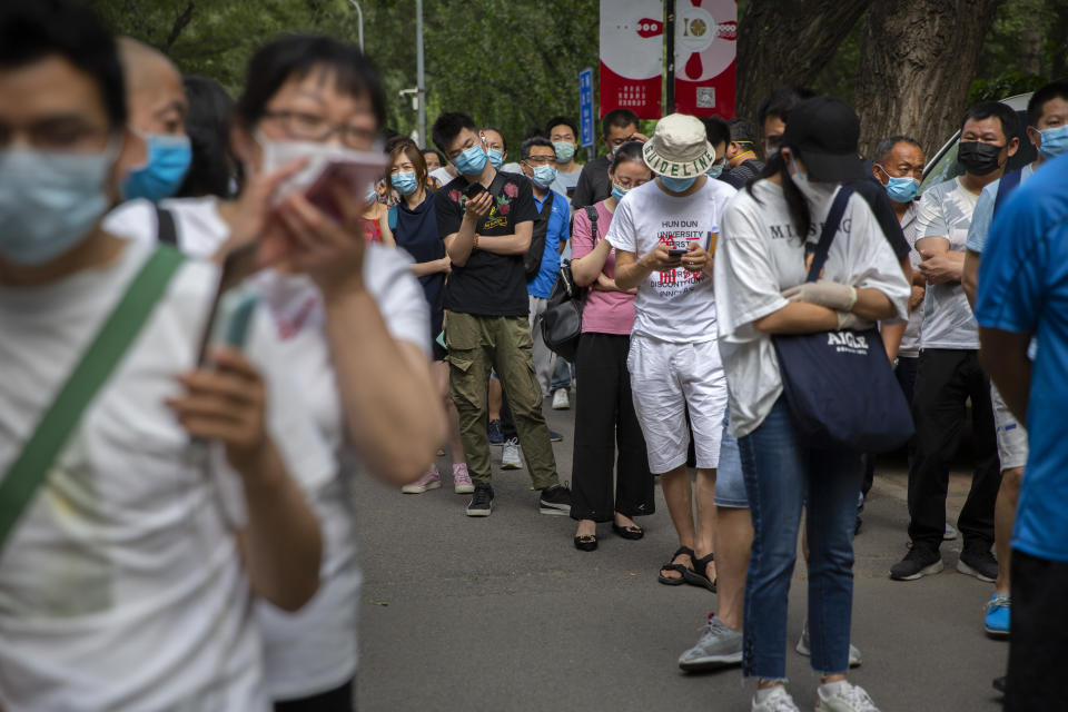 People wait in line at a COVID-19 testing site after they were ordered by the government to be tested after potentially being exposed to the coronavirus outbreak at a wholesale food market in Beijing, Wednesday, June 17, 2020. As the number of cases of COVID-19 in Beijing climbed in recent days following an outbreak linked to a wholesale food market, officials announced they had identified hundreds of thousands of people who needed to be tested for the coronavirus. (AP Photo/Mark Schiefelbein)