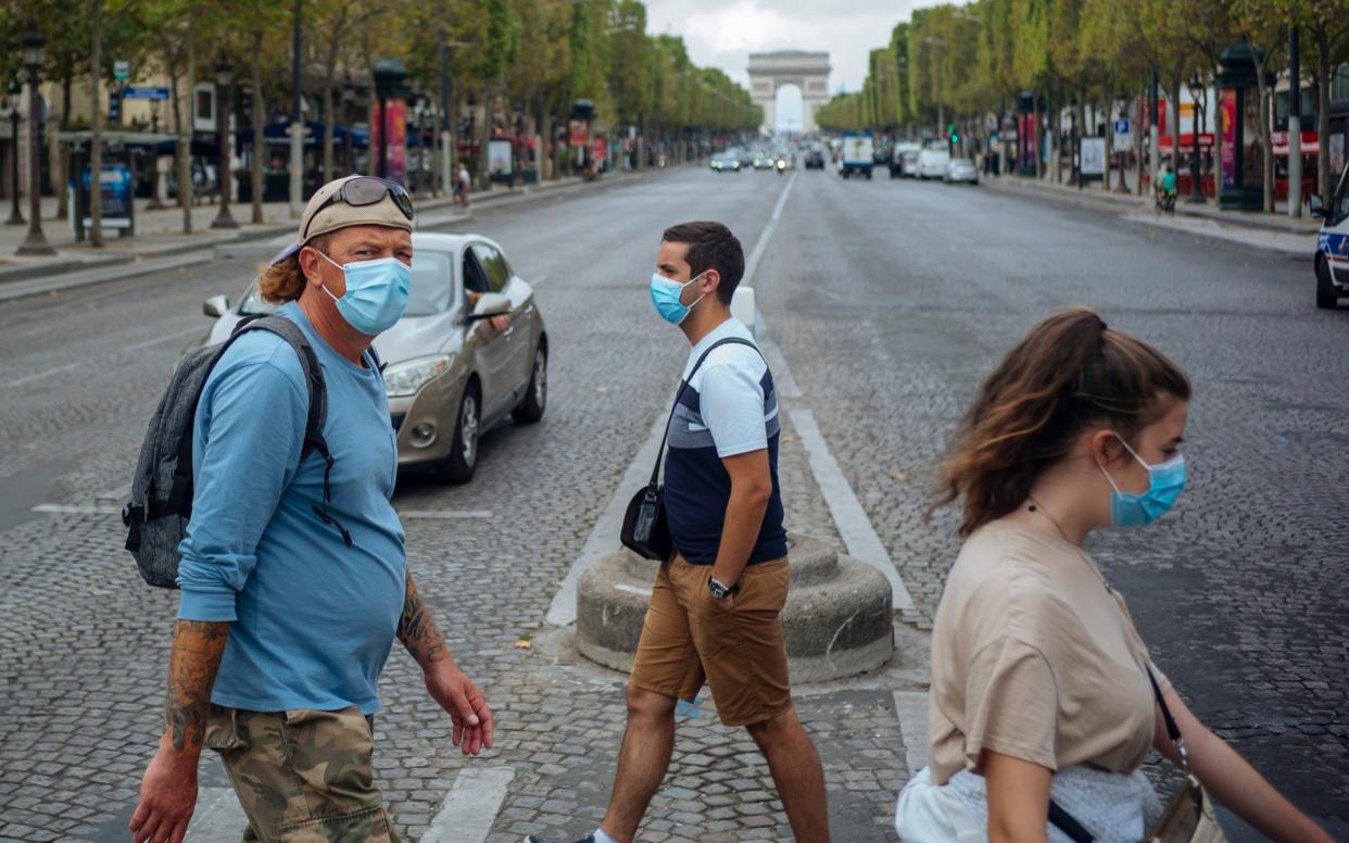 People with face masks cross the Champs Elysee - AP Photo/Kamil Zihnioglu