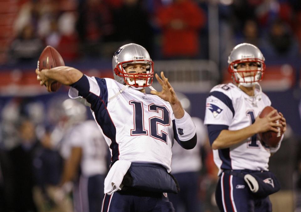 Two quarterbacks in warmup prepare to throw.