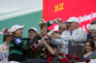 Trainer Kenneth McPeek, right, hand off the trophy to jockey Brian Hernandez Jr. as Hernandez celebrates in the winner's circle after riding Mystik Dan to win the 150th running of the Kentucky Derby horse race at Churchill Downs Saturday, May 4, 2024, in Louisville, Ky. (AP Photo/Jeff Roberson)