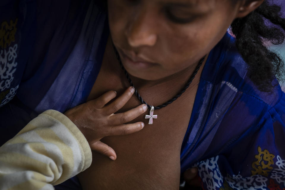 Tekien Tadese, 25, wearing an Ethiopian Orthodox Christian cross, holds her baby, Amanuel Mulu, 22 months old, who is suffering from malnutrition and weighs only 6.7 kilograms (14 pounds and 12 ounces), at the Ayder Referral Hospital in Mekele, in the Tigray region of northern Ethiopia, on Monday, May 10, 2021. The child was unconscious when he was first admitted in April, severely malnourished and anemic after losing half his body weight. Two weeks in intensive care saved his life. (AP Photo/Ben Curtis)